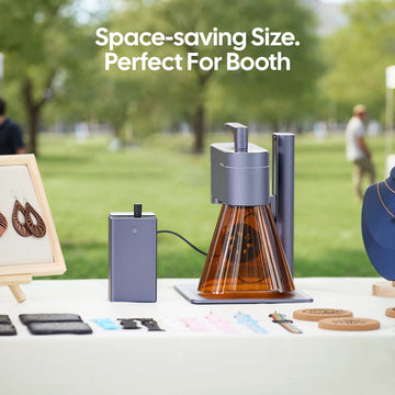LaserPecker laser engraver set up at an outdoor craft booth, highlighting its compact, space-saving design ideal for markets and pop-up events, paired with a portable power supply and sample engraved crafts.