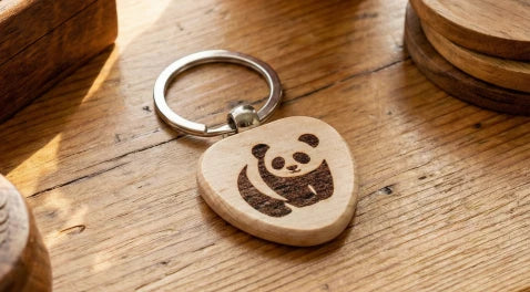A custom DIY wooden keychain being engraved with the LP1 Plus, featuring blank wood tags for personalized branding.