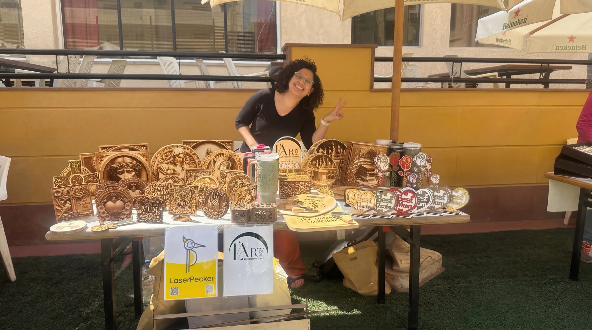 Personalized wooden ornaments being engraved and displayed at a market booth.