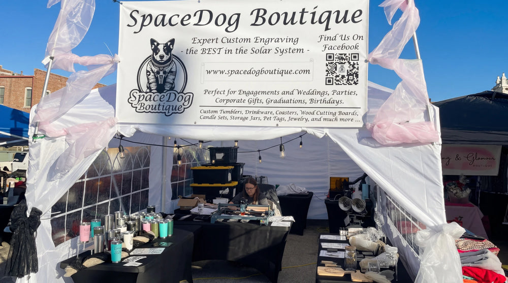 A vendor presenting engraved products from their self-designed brand at a market booth.