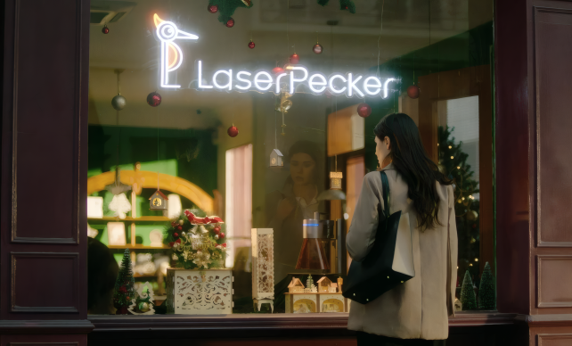 A woman standing outside a LaserPecker storefront window, captivated by the personalized engraved products displayed inside.