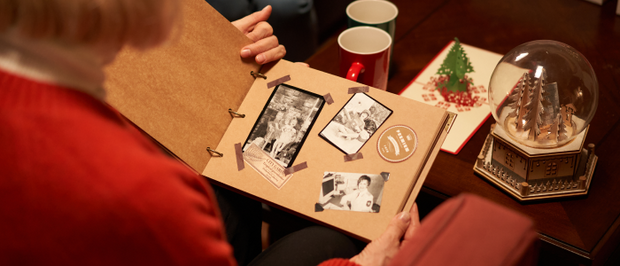 People viewing a handmade photo album in a Christmas setting.