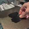 A Maker using a laser engraver to etch a detailed car graphic onto a 3D printed flexible TPU keychain
